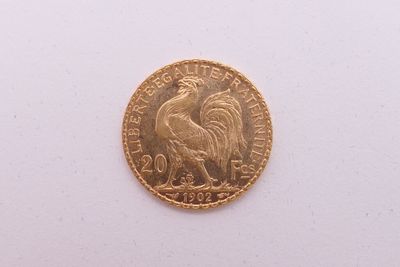 une pièce d'or représentant un coq sur un fond blanc