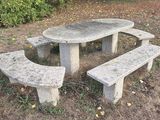 une table et un banc en pierre au milieu d'un champ