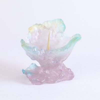 une petite fleur en verre d'où sort un bâtonnet doré