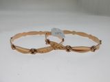 pair of gold tone bracelets on white background with price tag