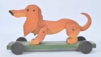un jouet en bois représentant un teckel sur un skateboard