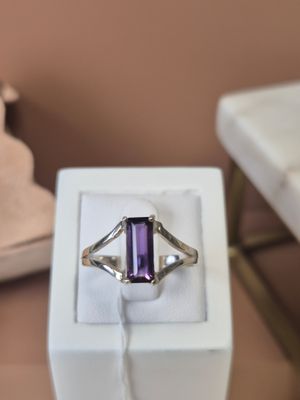 une bague sertie d'une pierre violette, posée sur une boîte blanche
