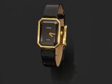 une montre noire et dorée avec un cadran carré sur fond noir