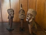 trois figurines en bois posées sur une étagère en bois dans une pièce