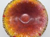 a red and yellow bowl sitting on a white surface