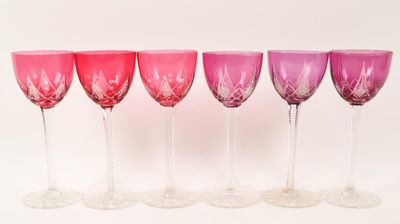six verres à vin sont alignés sur une surface blanche