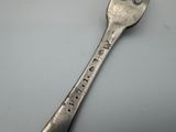 a silver spoon with writing on it sitting on a table