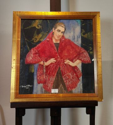 un tableau représentant une femme portant un châle rouge, posé sur un chevalet