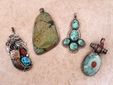 un ensemble de quatre pendentifs en pierres turquoise et rouges posés sur une table