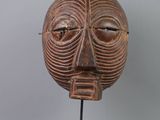 gros plan d'un masque en bois sur un support sur fond blanc