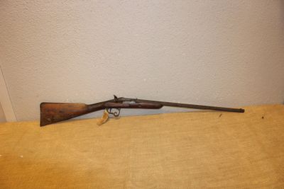 Un vieux fusil est posé sur une table près d'un mur.