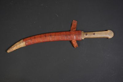 a close up of a knife with a wooden handle on a black surface