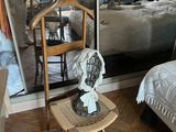 une petite table sur laquelle est posé un ventilateur, à côté d'un lit