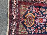 an old persian rug on the floor next to a wall