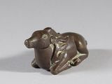 une vieille figurine en bronze représentant une vache avec une selle