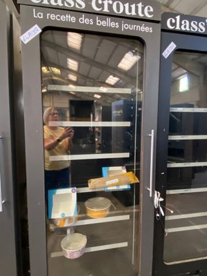 a woman standing in front of a glass door with food inside of it