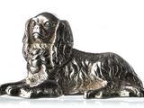 figurine de chien argentée assise sur une surface blanche, sur fond blanc