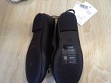 pair of black shoes on a wooden floor with a price tag