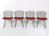 trois chaises en fil de fer noires avec des coussins rouges sur fond blanc