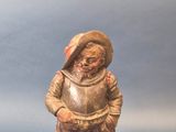 une petite figurine représentant un garçon coiffé d'un chapeau