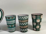 three cups and a jug are sitting on a white surface