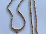 collier composé d'une pièce d'or suspendue à une chaîne, sur un fond blanc