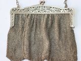 an antique silver metal purse with fringes hanging on a wall