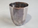 a silver cup that is sitting on a white surface