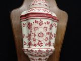 a red and white vase on a wooden stand