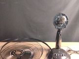 une table sur laquelle se trouvent un ventilateur et un téléphone