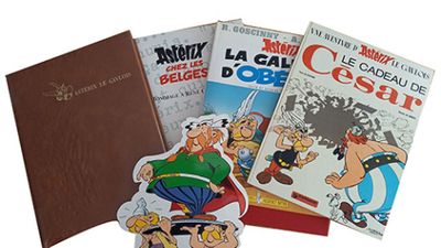Plusieurs albums de bandes dessinées sont empilés les uns sur les autres sur une surface blanche