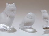 trois figurines représentant des chats et un oiseau posées sur une table