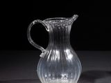 a glass pitcher sitting on a table with a black background