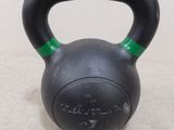 un kettlebell noir avec une poignée verte posé sur une table