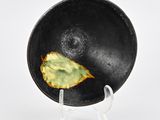 a black plate with a leaf on it on a stand