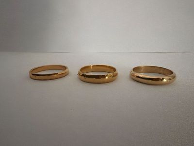 three gold rings sitting on top of a white surface