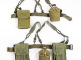trois pochettes militaires et une paire de ciseaux accrochés au mur