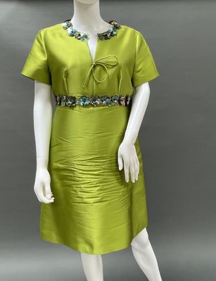 a mannequin wearing a green dress with beading on the neck