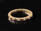 a close up of a gold ring with red stones on a black surface