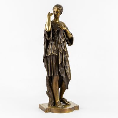une statue en bronze représentant une femme tenant un verre à la main