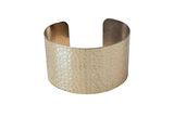 a close up of a gold cuff bracelet on a white background