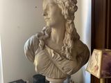 a bust of a woman sitting on a table next to a lamp