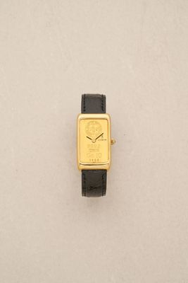 an image of a gold watch with a black strap on a white surface