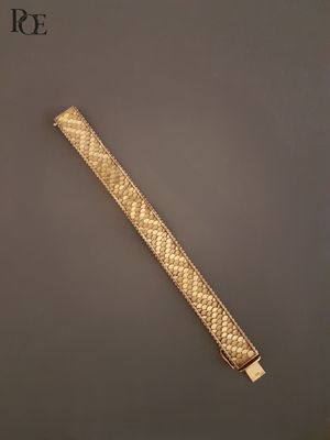 gros plan d'un bracelet en or sur une surface grise