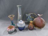 de nombreux vases de formes variées posés sur une table, sur fond gris