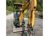 the back end of a yellow excavator sitting on top of a pile of dirt