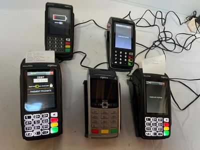 Plusieurs téléphones portables sont alignés sur une table, reliés par des fils.