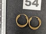 Deux paires de boucles d'oreilles créoles en or sont présentées à côté d'une règle.