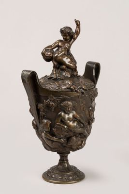a bronze statue of a boy sitting on a vase