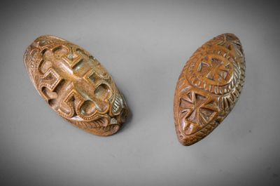 deux boutons en bois sculptés, ornés de motifs, posés sur une table